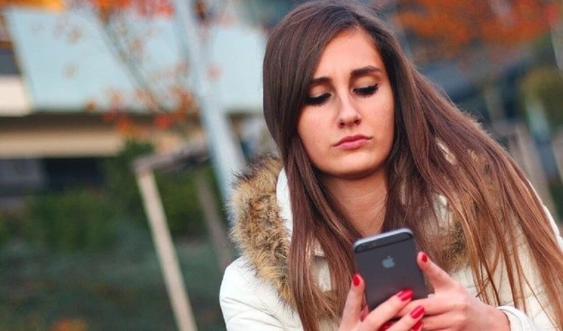 Mulher séria e desanimada conversando no WhatsApp